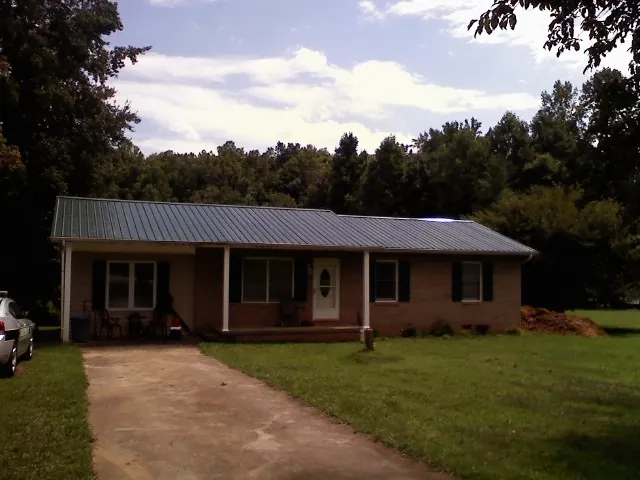 Dark green metal roof on a brick ranch with a covered porch in Lafayette
