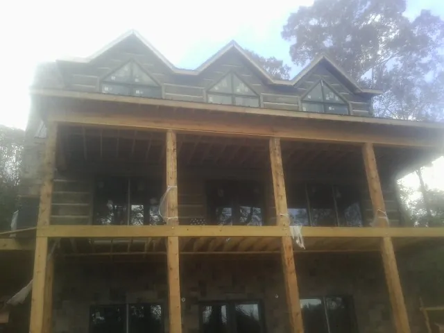 Dormers and porch framing on a large log home under construction — Roof Coating work by our crew in Lafayette